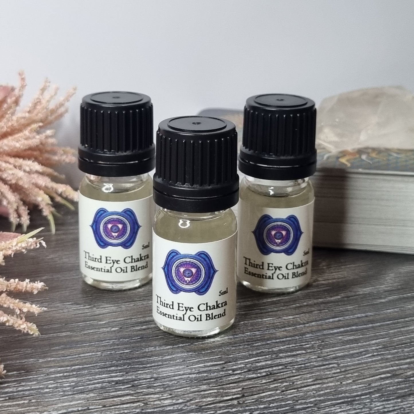 Three essential oil bottles labeled 'Third Eye Chakra' on a wooden surface.