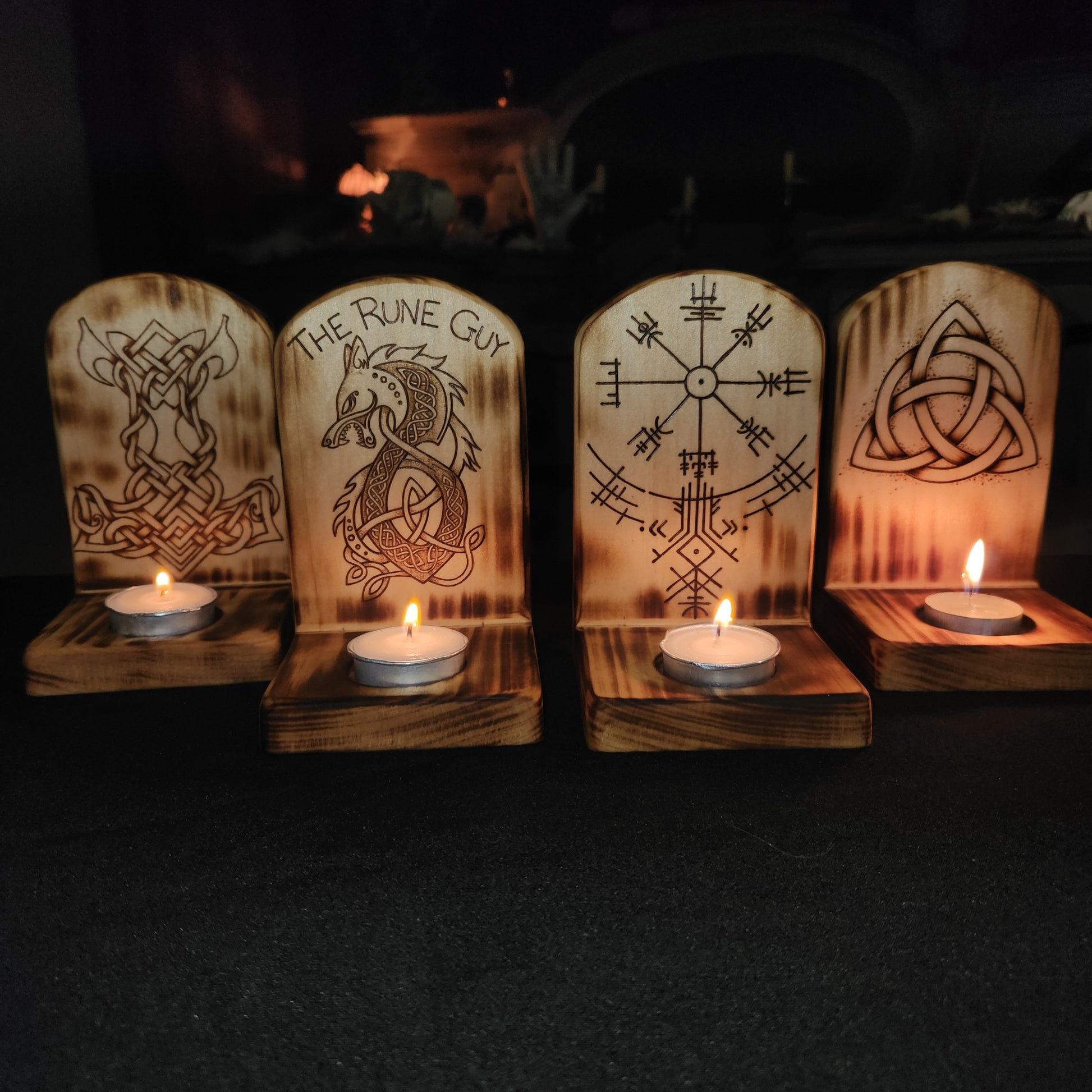 Wooden candle holders with engraved designs on a dark background