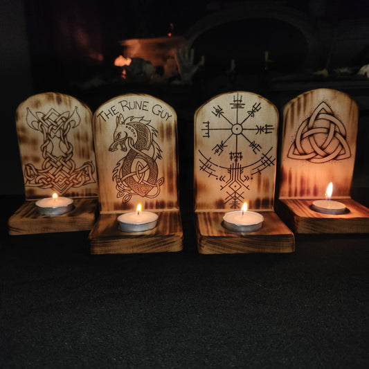 Wooden candle holders with engraved designs on a dark background