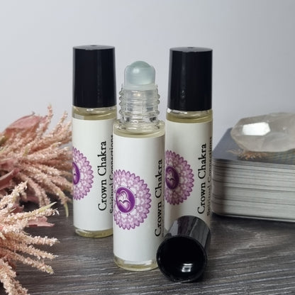 Three rollerball bottles with a purple flower design on a wooden surface.